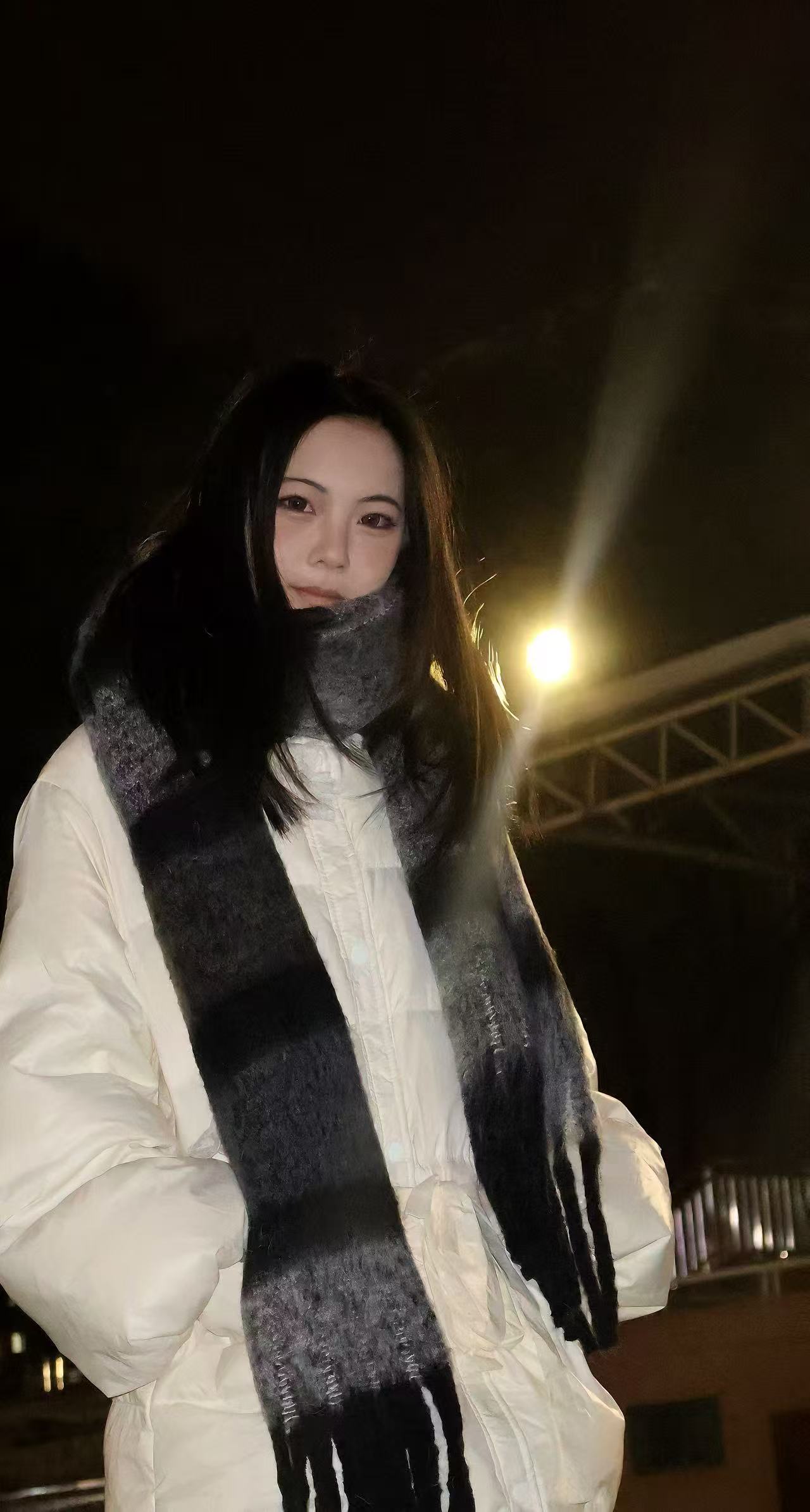 张威穿着白色外套围着围巾的夜晚照片